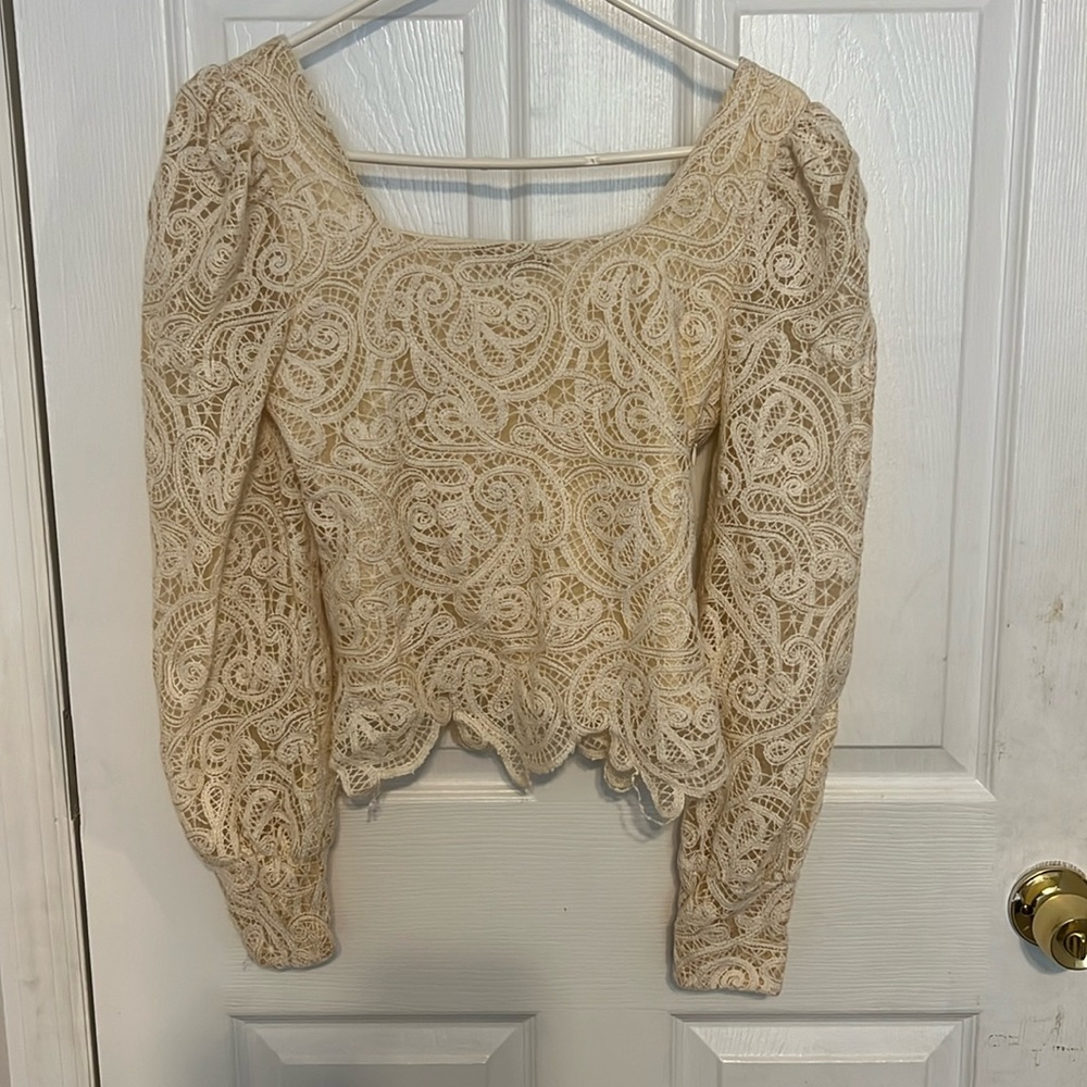 Cream colored blouse with a square neckline and shoulder